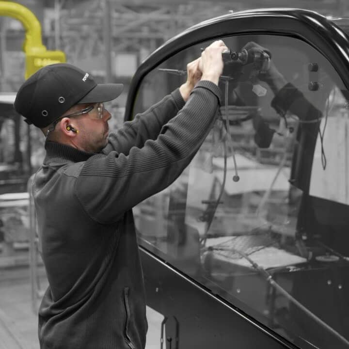 A man in a black hat is working on a car window.